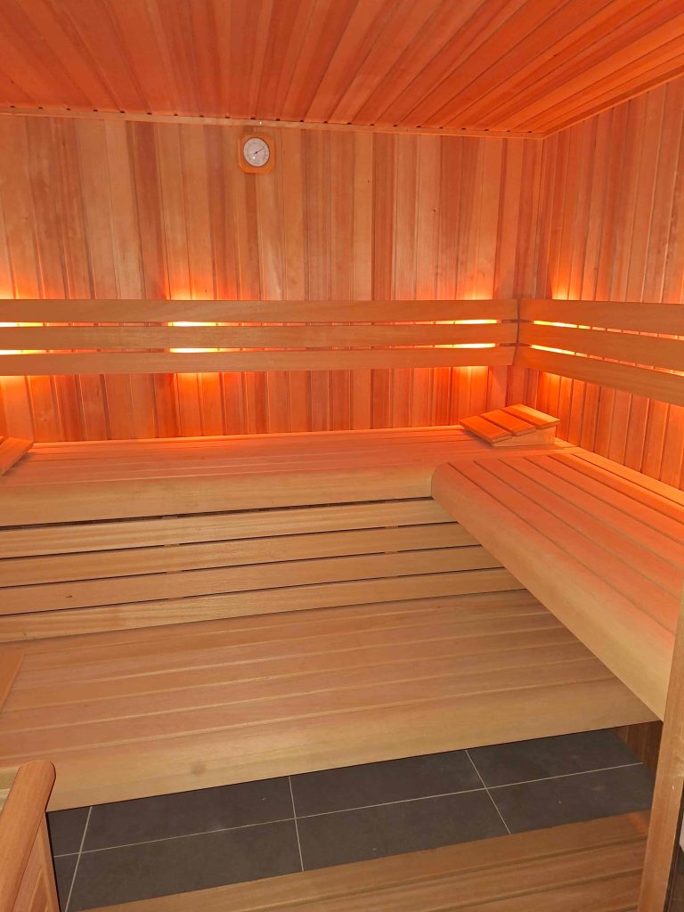 Binnenkant van houten sauna met zitbanken en warme verlichting