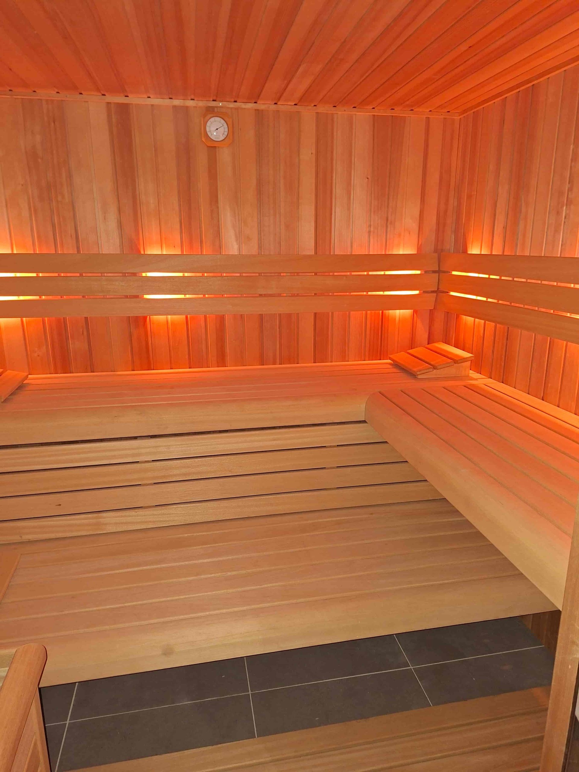 Binnenkant van houten sauna met zitbanken en warme verlichting