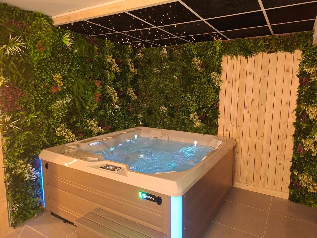 Jacuzzi met water, sfeerverlichting en groene plantenwand